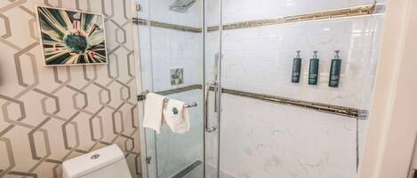 A modern bathroom with a glass shower enclosure, a toilet, and a towel rack.