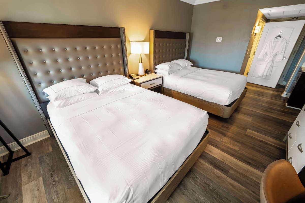 Ett hotellrum med två sängar, ett trägolv och en badrock som hänger på dörren.