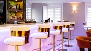 A bar area with multiple stools, a shelf with bottles, and a counter. - Hilton St. Augustine Historic Bayfront (St. Augustine)