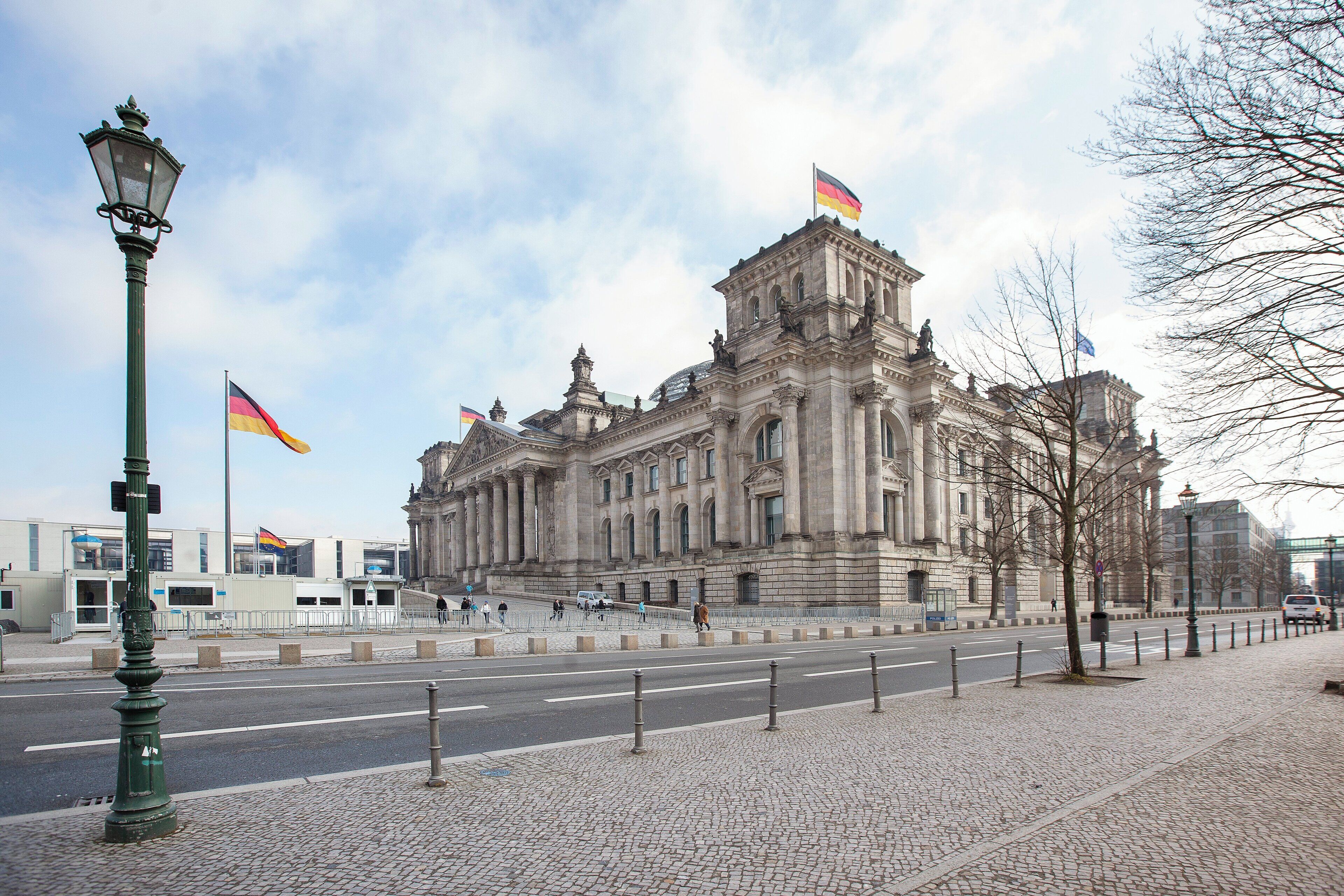 A historic building with classical architecture, a paved walkway, and flags.