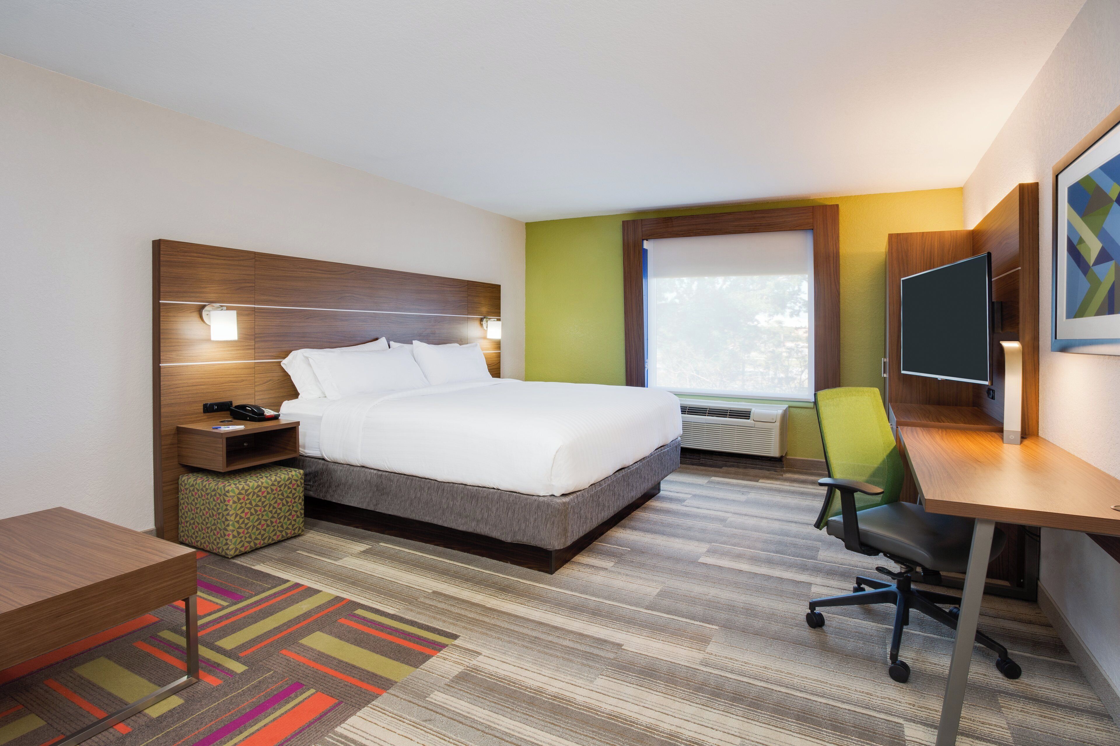 Ein Hotelzimmer mit Bett, Nachttisch, Stuhl, Schreibtisch und Fenster.