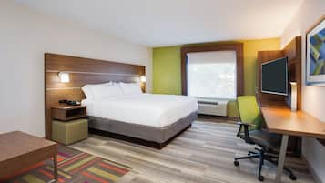 Ein Hotelzimmer mit Bett, Nachttisch, Stuhl, Schreibtisch und Fenster.