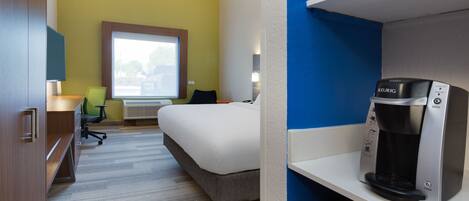Une chambre d’hôtel équipée d’un lit, d’un bureau, d’une chaise, d’une machine à café et d’une fenêtre donnant sur un paysage agréable.