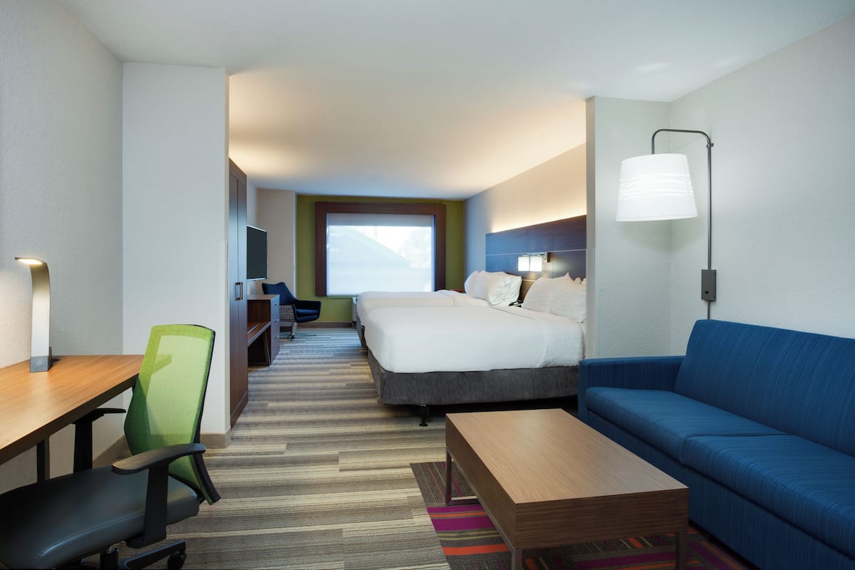 A hotel room with a bed, a sofa, a desk, and a chair.