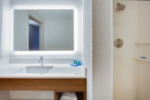 Ein Badezimmer mit weißem Waschbecken, Spiegel und Dusche.
