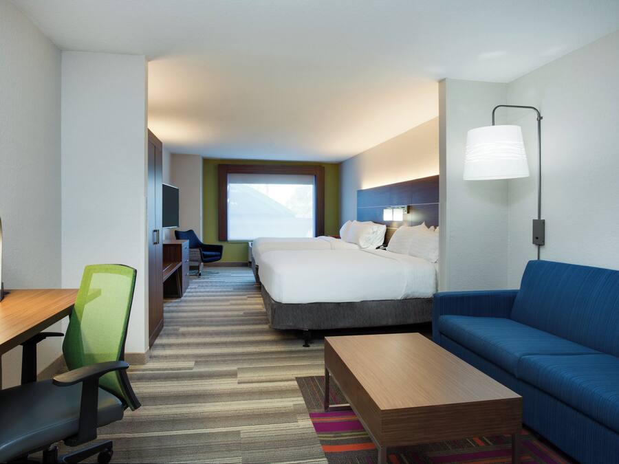 Una habitación de hotel con cama, escritorio, silla, sofá y lámpara.