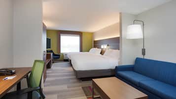 Hotellihuone, jossa on sänky, työpöytä, tuoli, sohva ja lamppu.