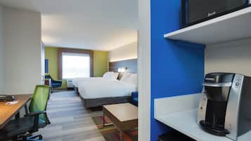 A hotel room with a bed, a desk with a chair, a microwave, and a coffee maker.