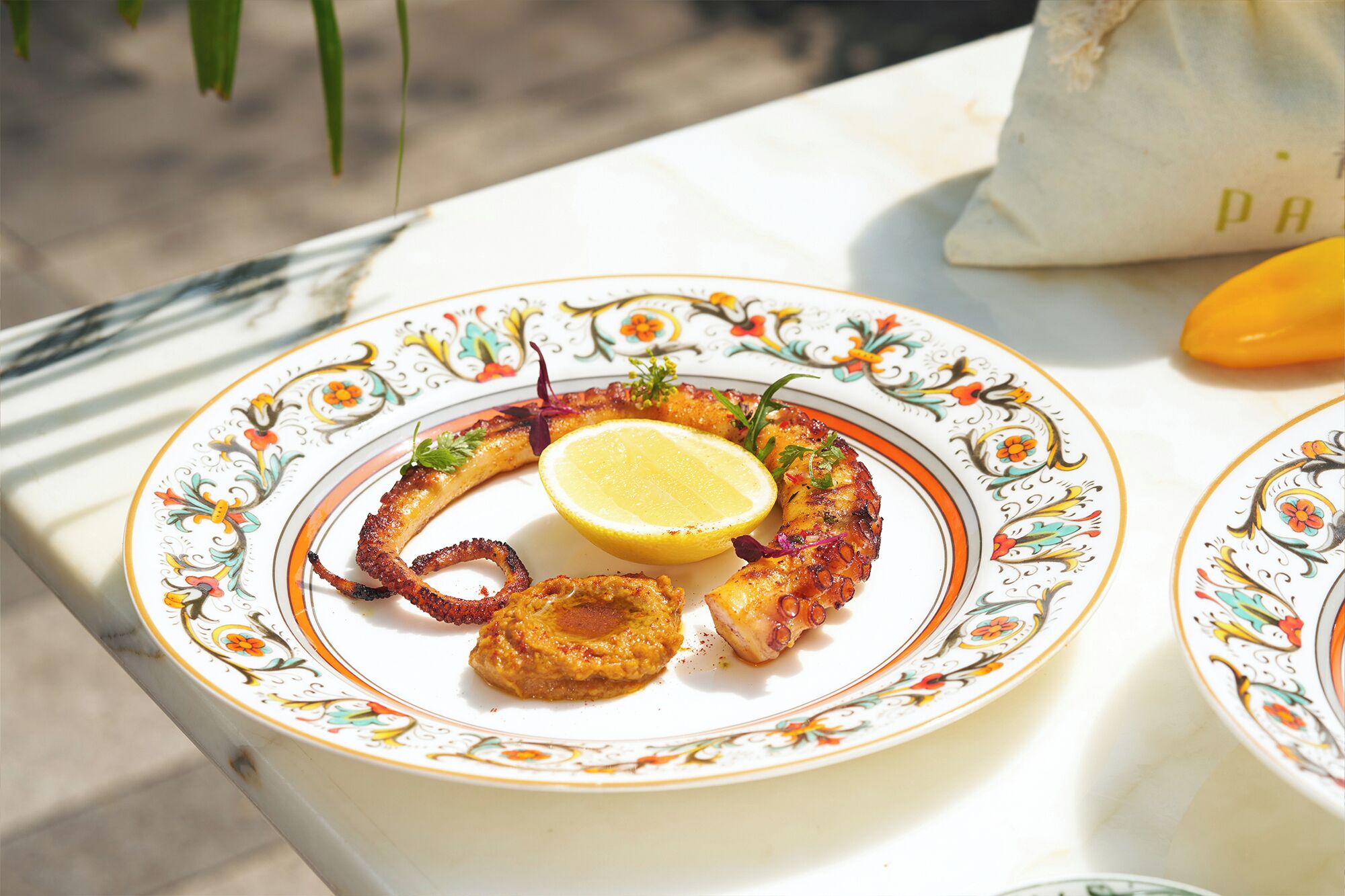 A plate of food with a lemon wedge, possibly seafood, on a decorative plate.