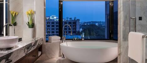 Un baño moderno con una bañera grande, un tocador doble y una mampara de cristal.