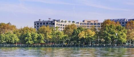 A waterfront hotel with multiple buildings, trees, and a calm body of water.