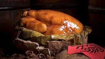 A roasted turkey on a wooden surface with a cloth and a red tag.