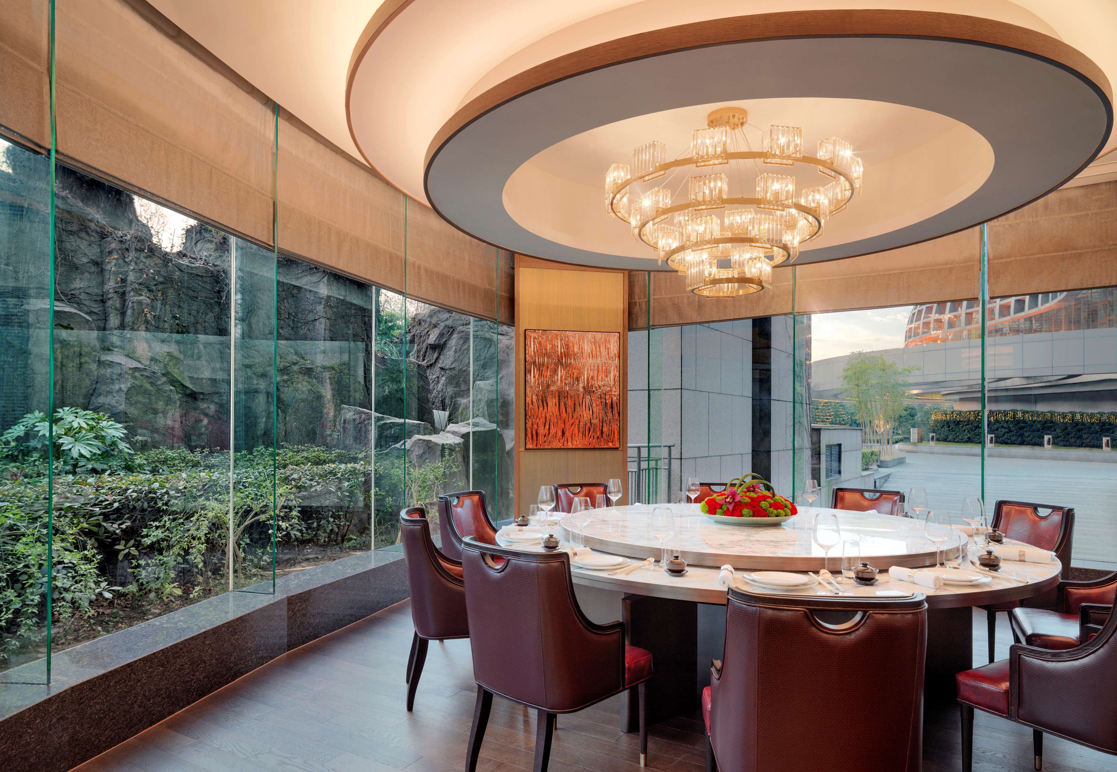 A modern dining area with a round table, chairs, and a chandelier.