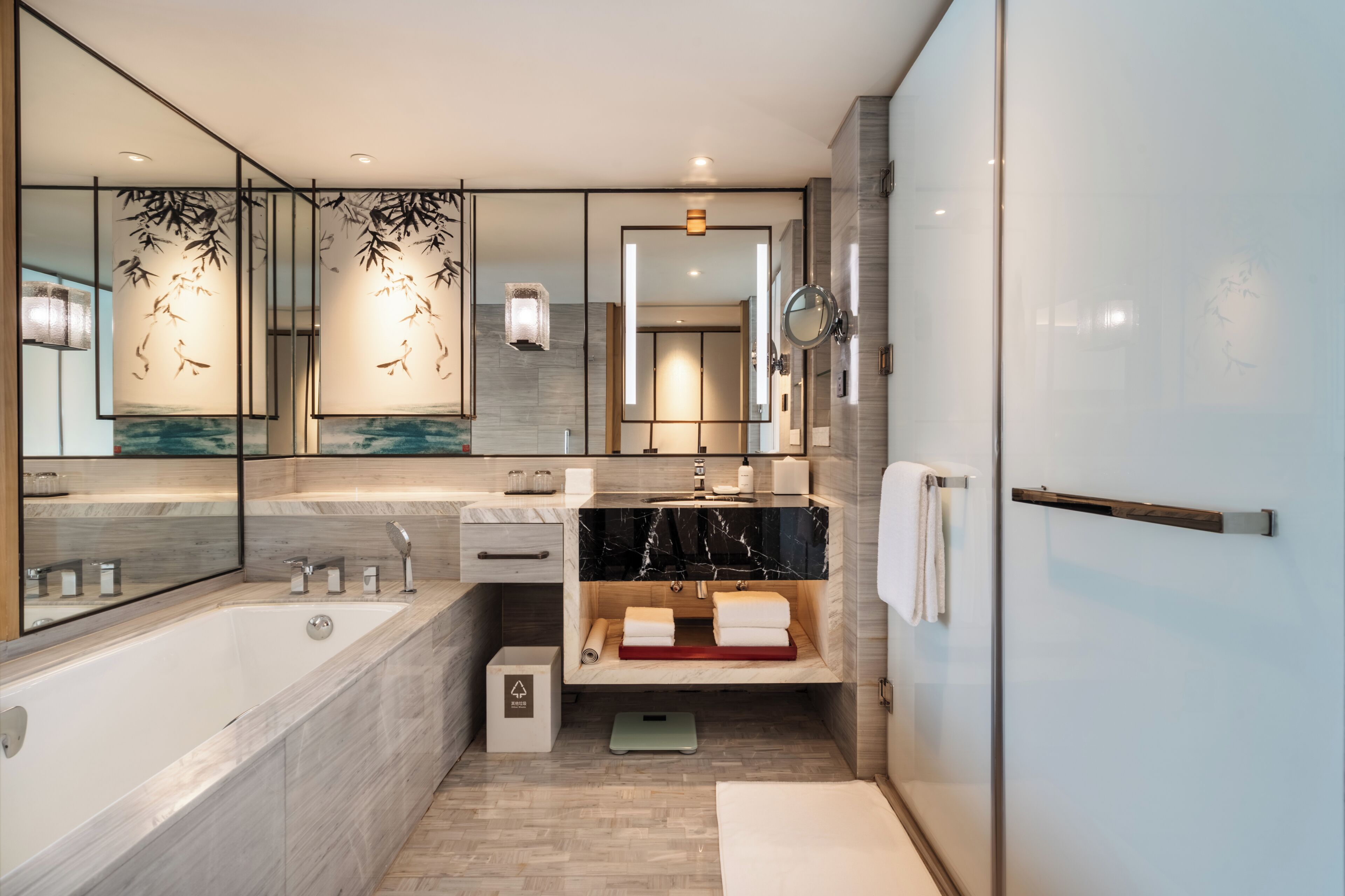 Une salle de bain moderne avec un grand miroir, une baignoire, un meuble-lavabo et un porte-serviettes.
