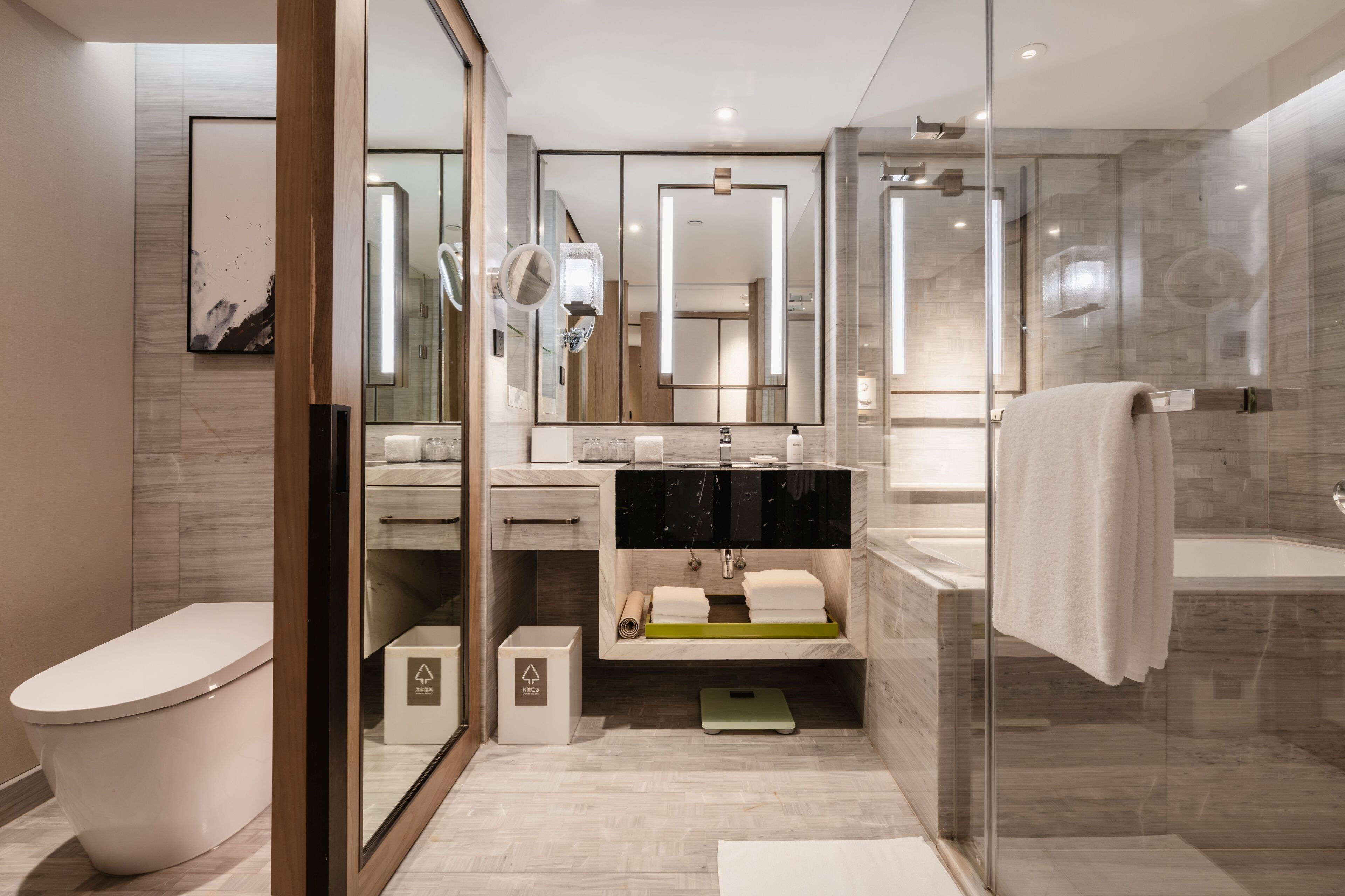 A modern bathroom with a glass shower enclosure, a freestanding bathtub, and a vanity with a mirror.