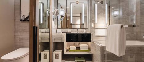 A modern bathroom with a glass-enclosed shower, a toilet, and a vanity with a mirror.
