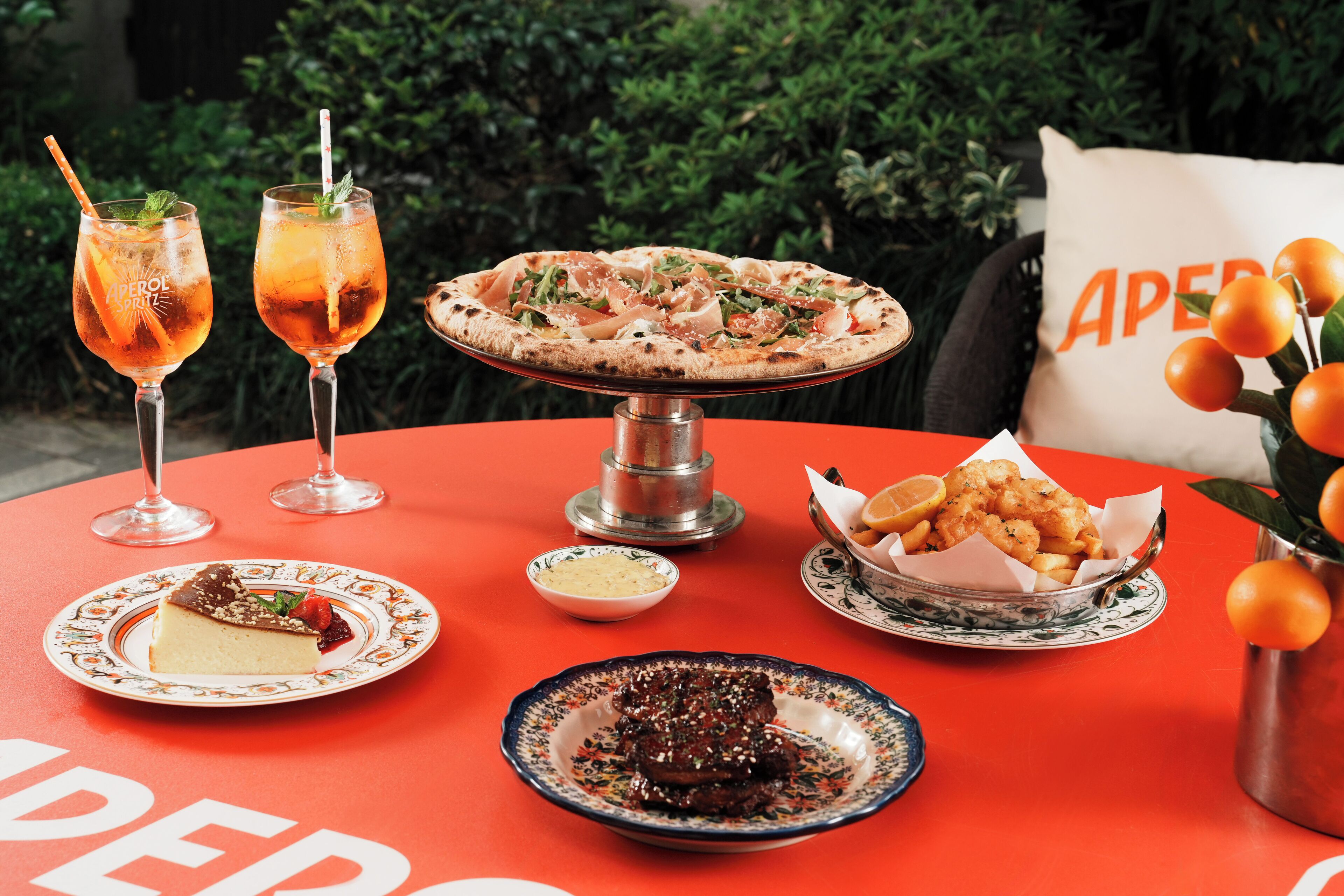 A table with a pizza, two drinks, a dessert, and a basket of fries.