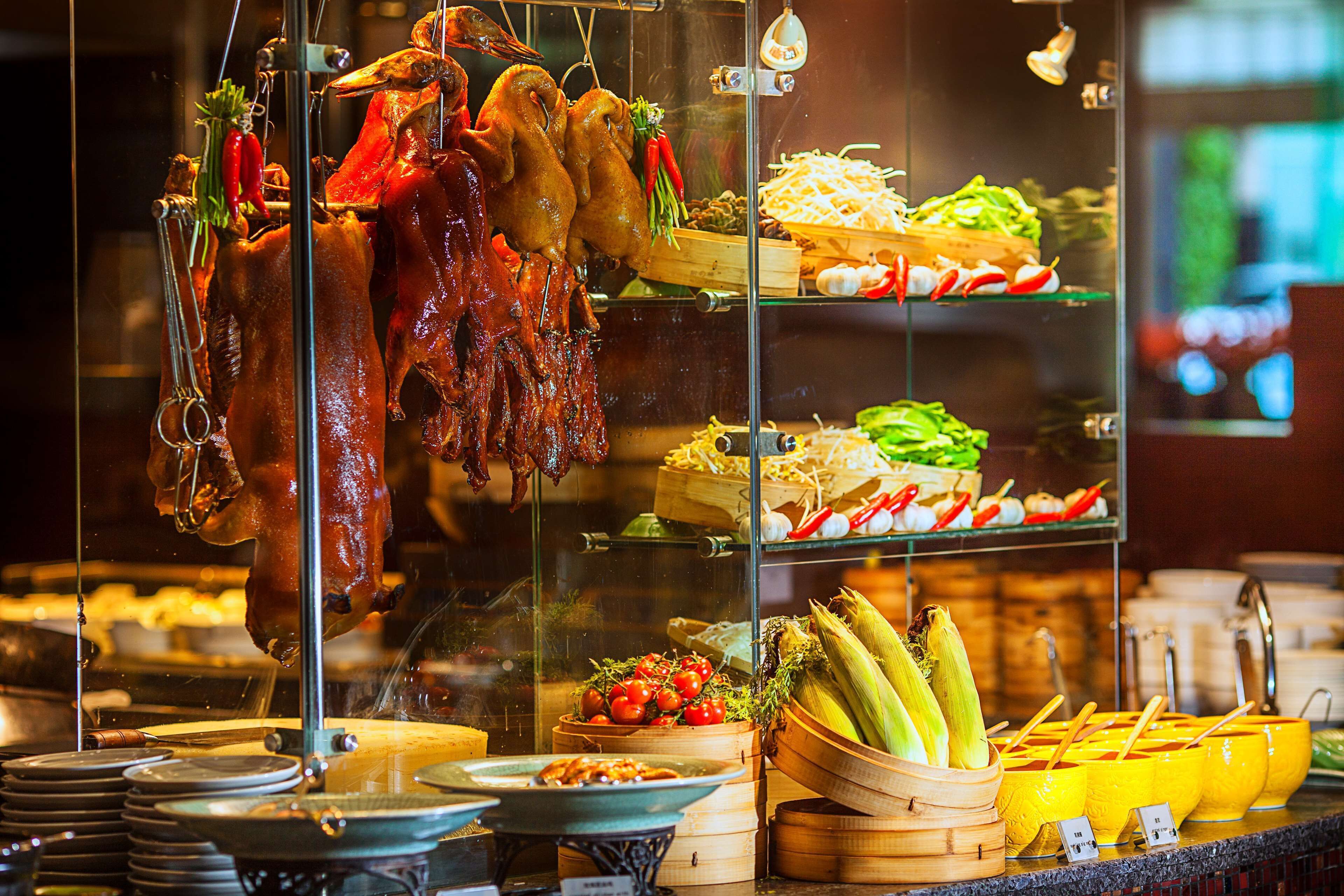A food display with roasted meats, vegetables, and various dishes.