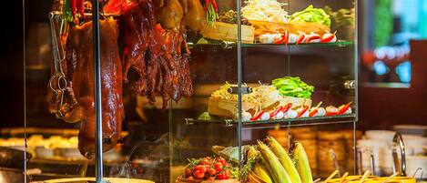 Una exhibición de alimentos con carnes asadas, verduras y diferentes platos.