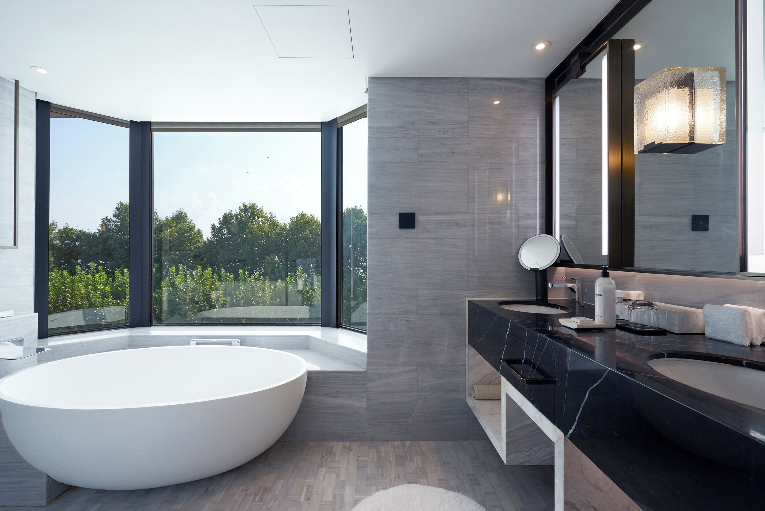 A modern bathroom with a large bathtub, two sinks, and a large mirror.