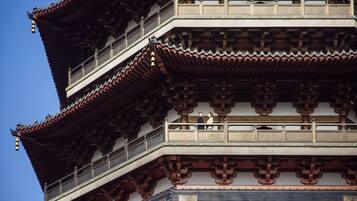 A traditional multi-tiered building with ornate wooden railings and a clear blue sky in the background.