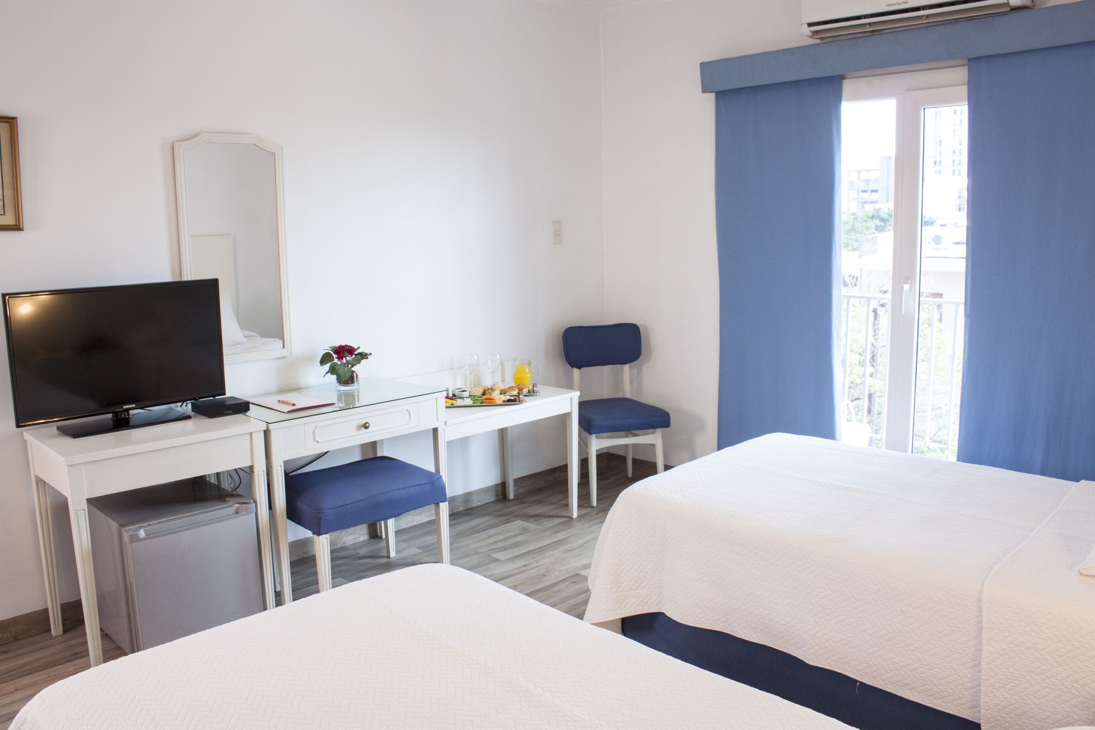 Habitación de hotel con una cama, un escritorio con computadora, una silla y un televisor.