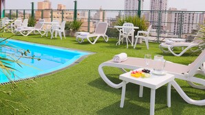A rooftop terrace with a swimming pool, white lounge chairs, and a table with fruits and drinks. - Hotel Cecilia (Asunción)