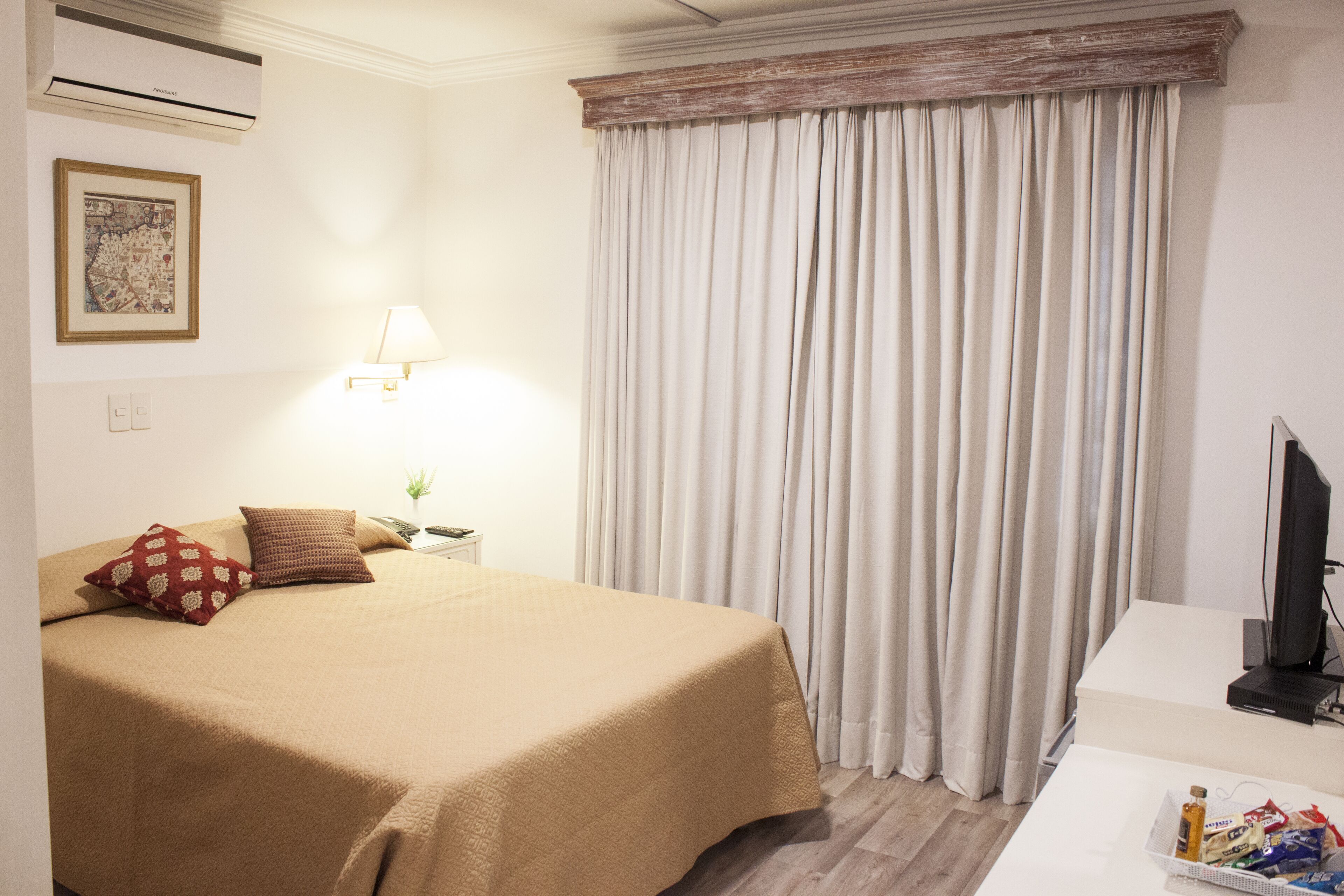 Una habitación de hotel con cama, escritorio, lámpara y televisión.