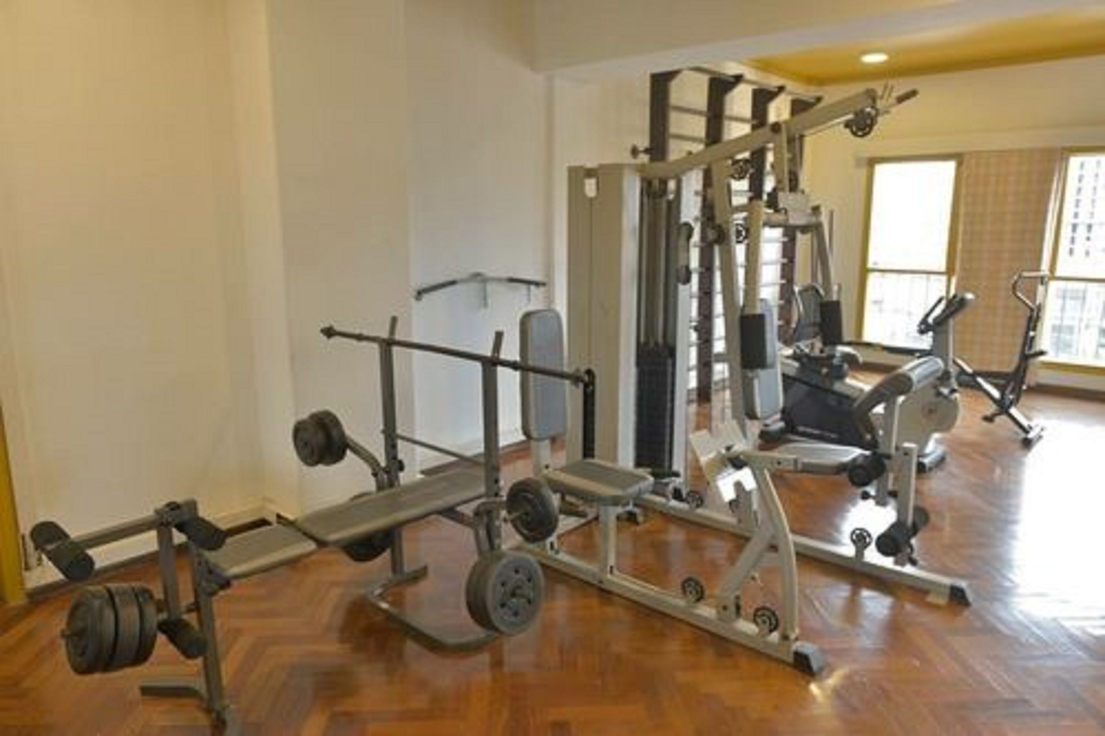 Et fitnessrum med forskellig træningsudstyr, herunder bænkpres, squatrack og vægtbænke.