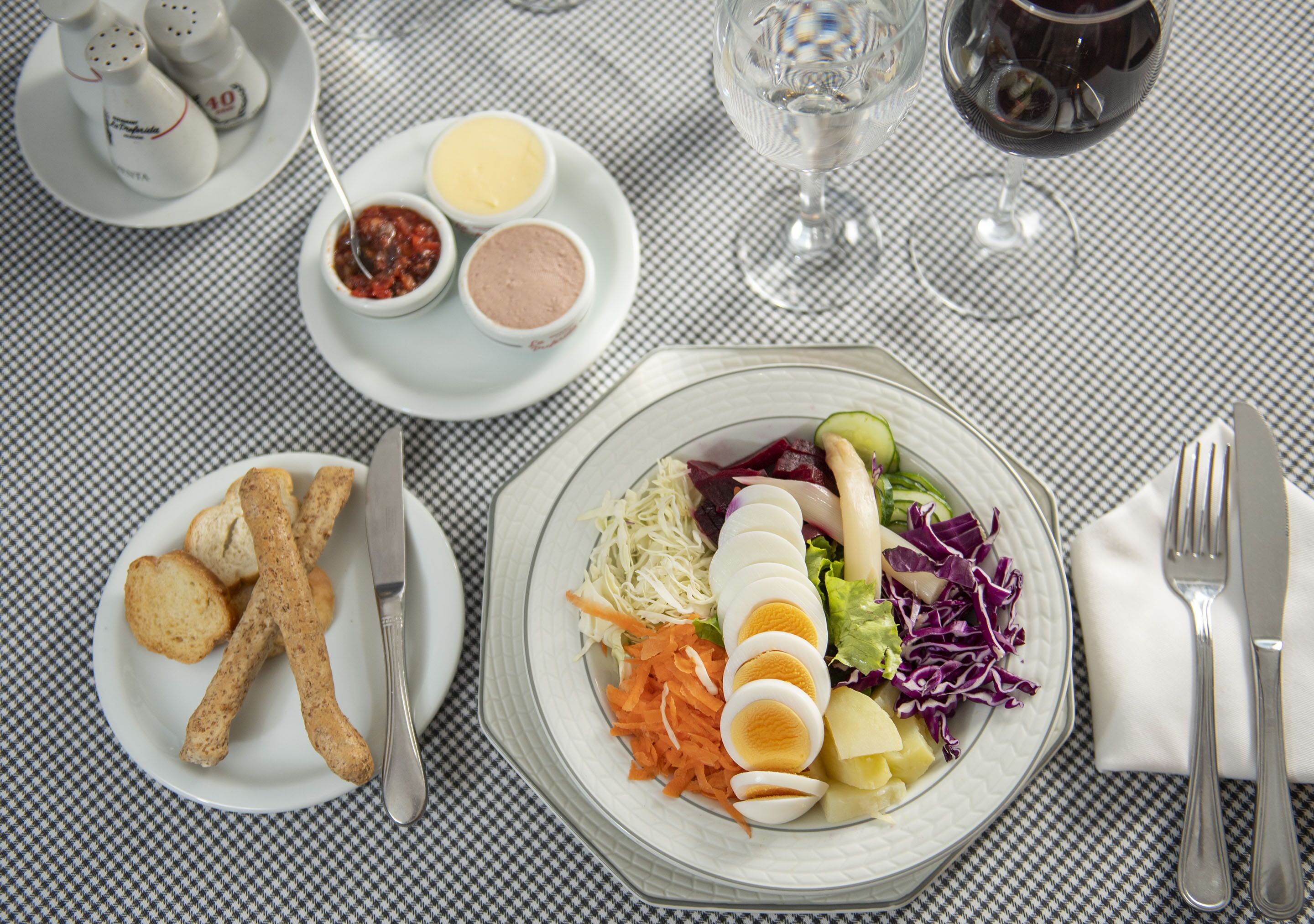 Una mesa servida con ensalada, palitos de pan y salsas.