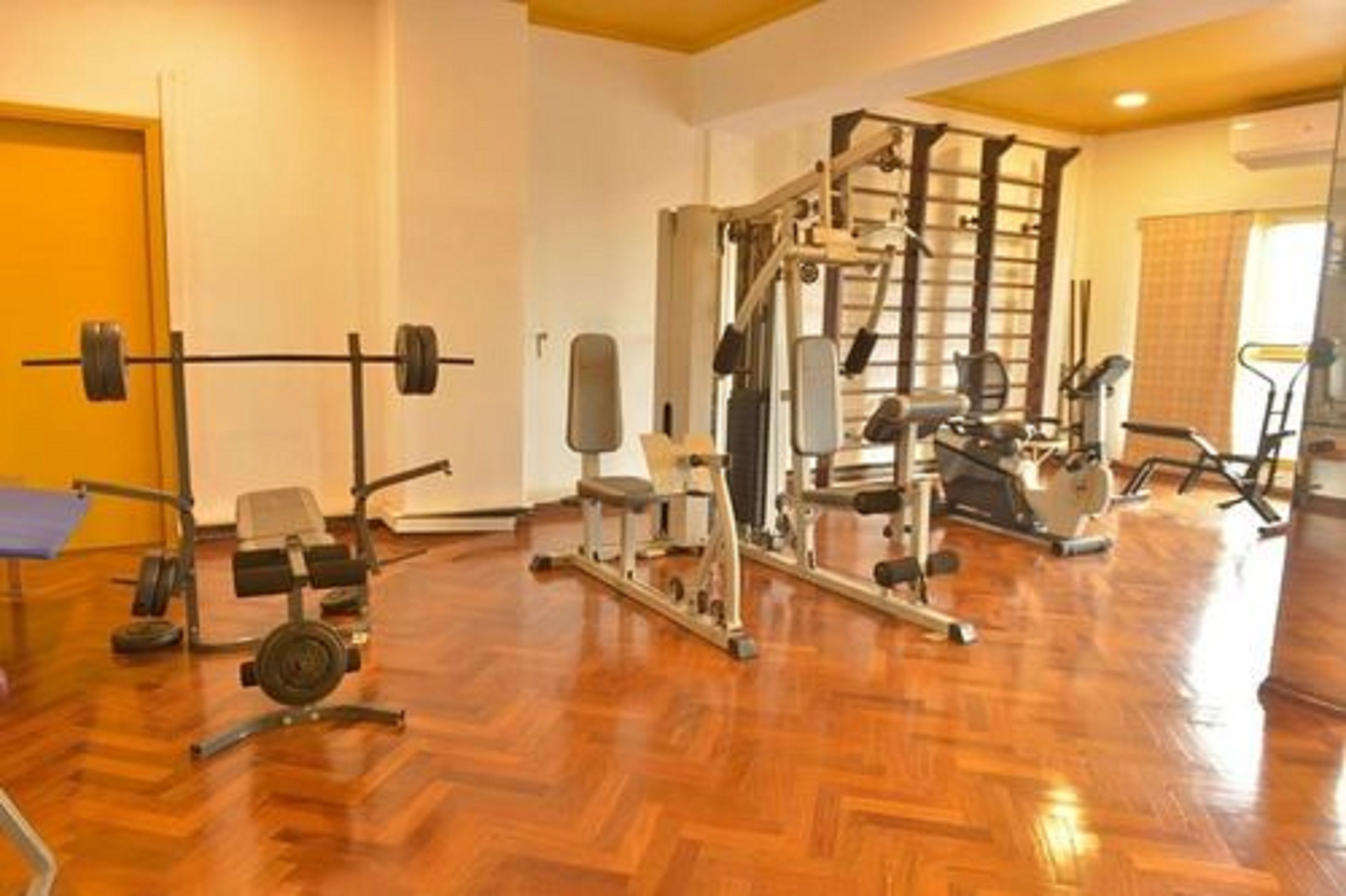 Une salle de sport équipée de divers appareils d’entraînement, notamment un support à squats, un banc de développé couché et des machines de musculation.