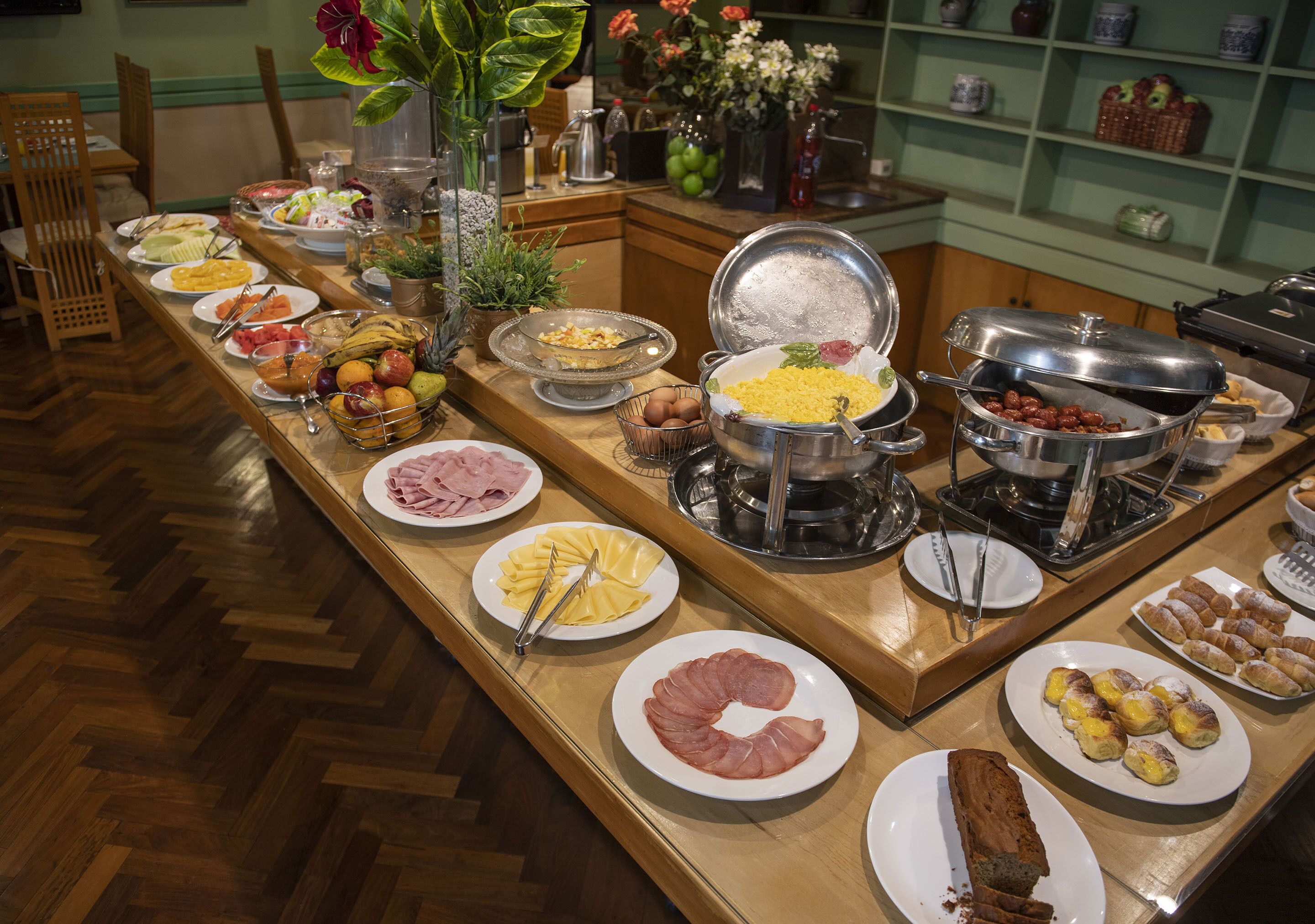 A buffet with various food items including fruits, meats, and pastries.