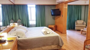 A hotel room with a bed, bedside table, lamp, and a television mounted on the wall. - Hotel Cecilia (Asunción)