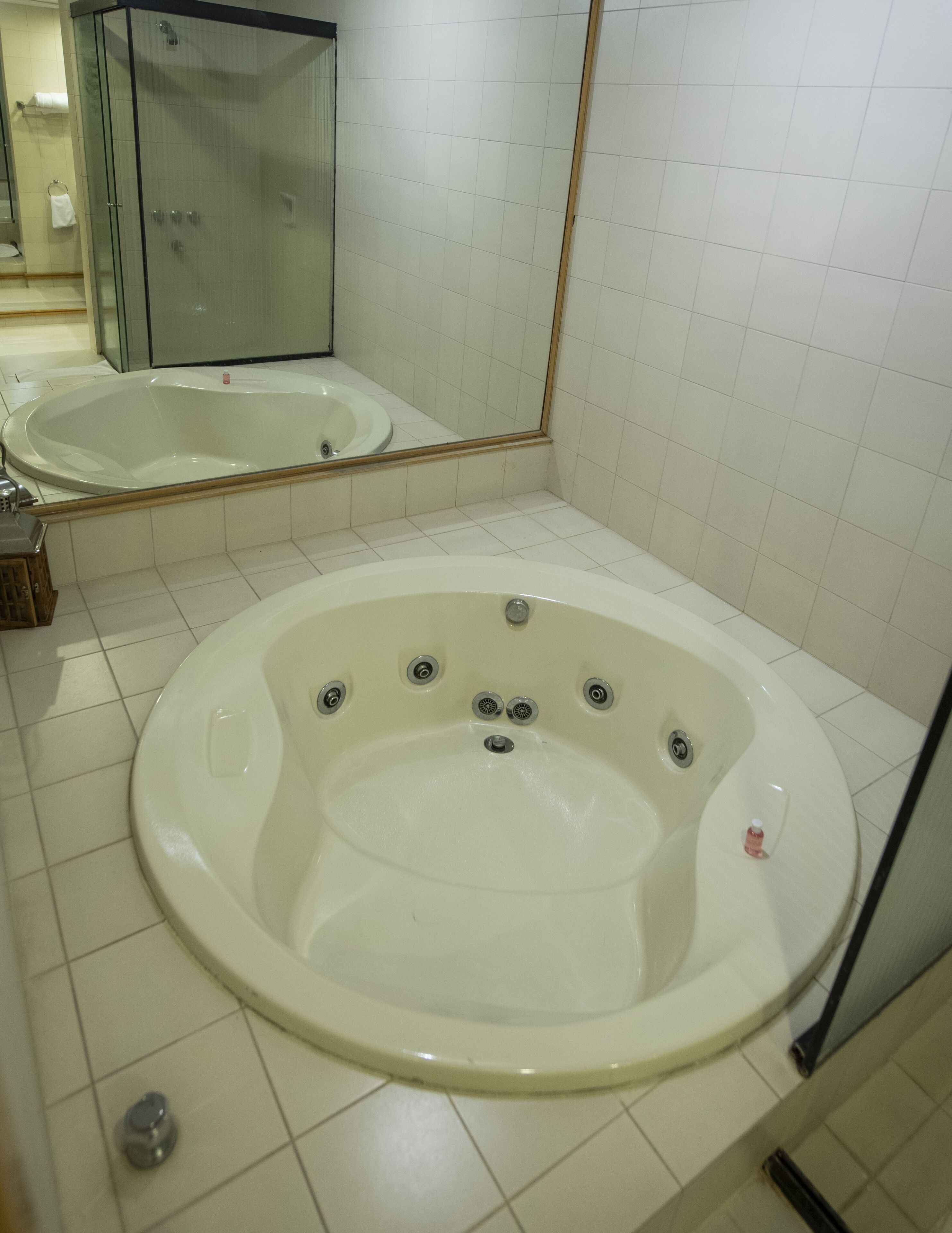 Un baño con una bañera grande, un lavamanos y un espejo.