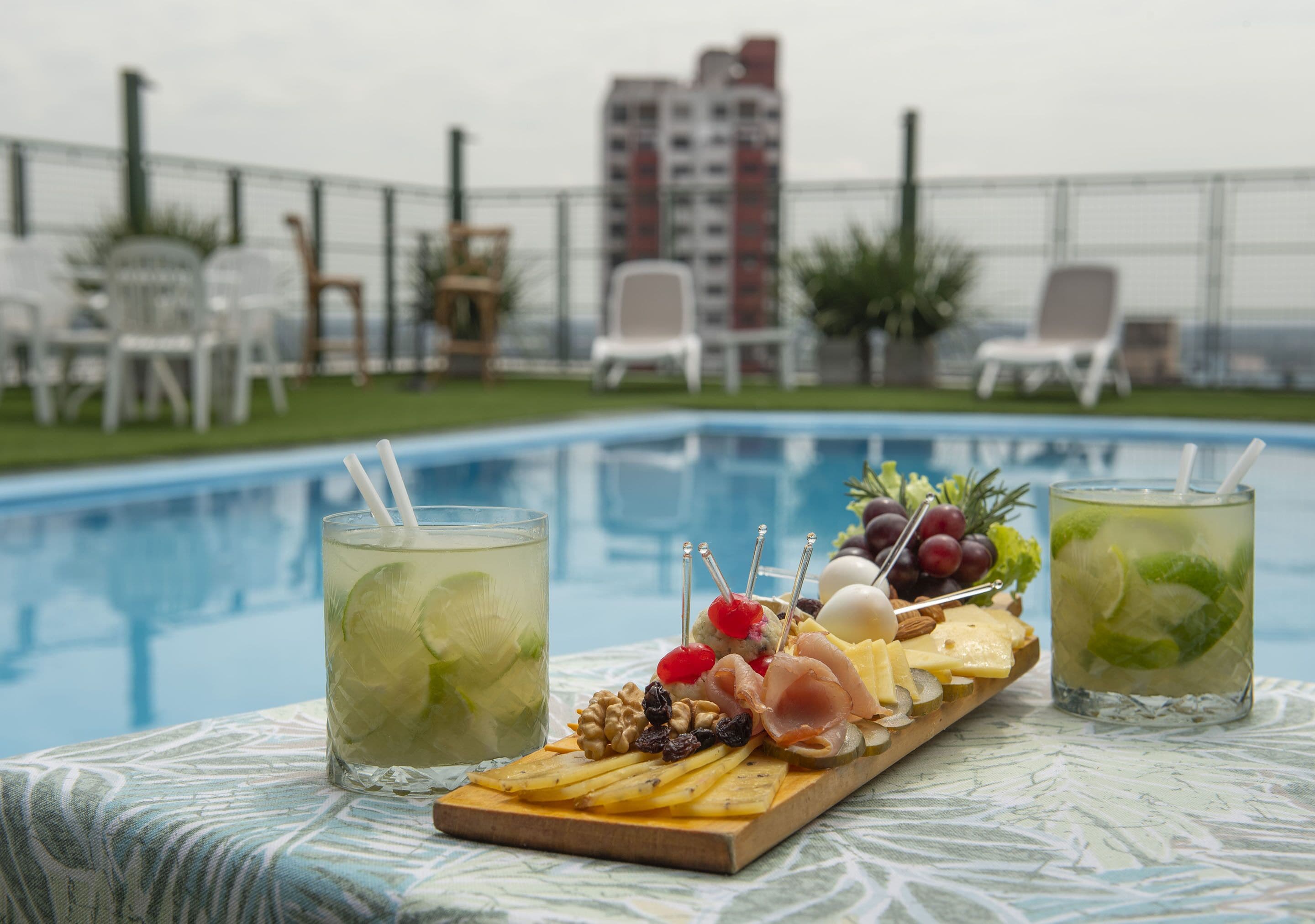A poolside setting with a charcuterie board, two drinks, and outdoor seating.
