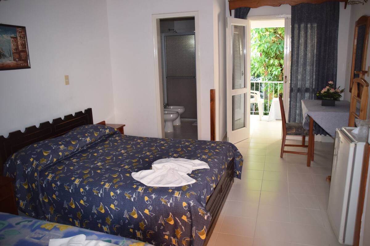 A bedroom with a bed, a bathroom, and a balcony.