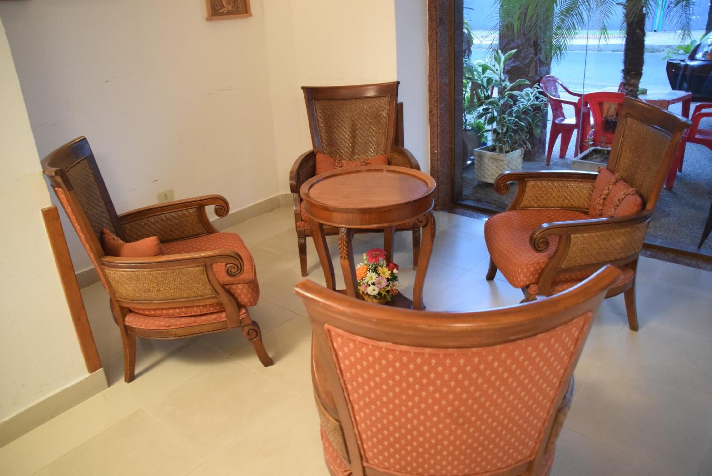 A seating area with wooden chairs and a table, a potted plant, and a view of the outdoors.