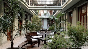 A courtyard with seating, potted plants, and a central table. - Up Tribeca Hotel (Buenos Aires)