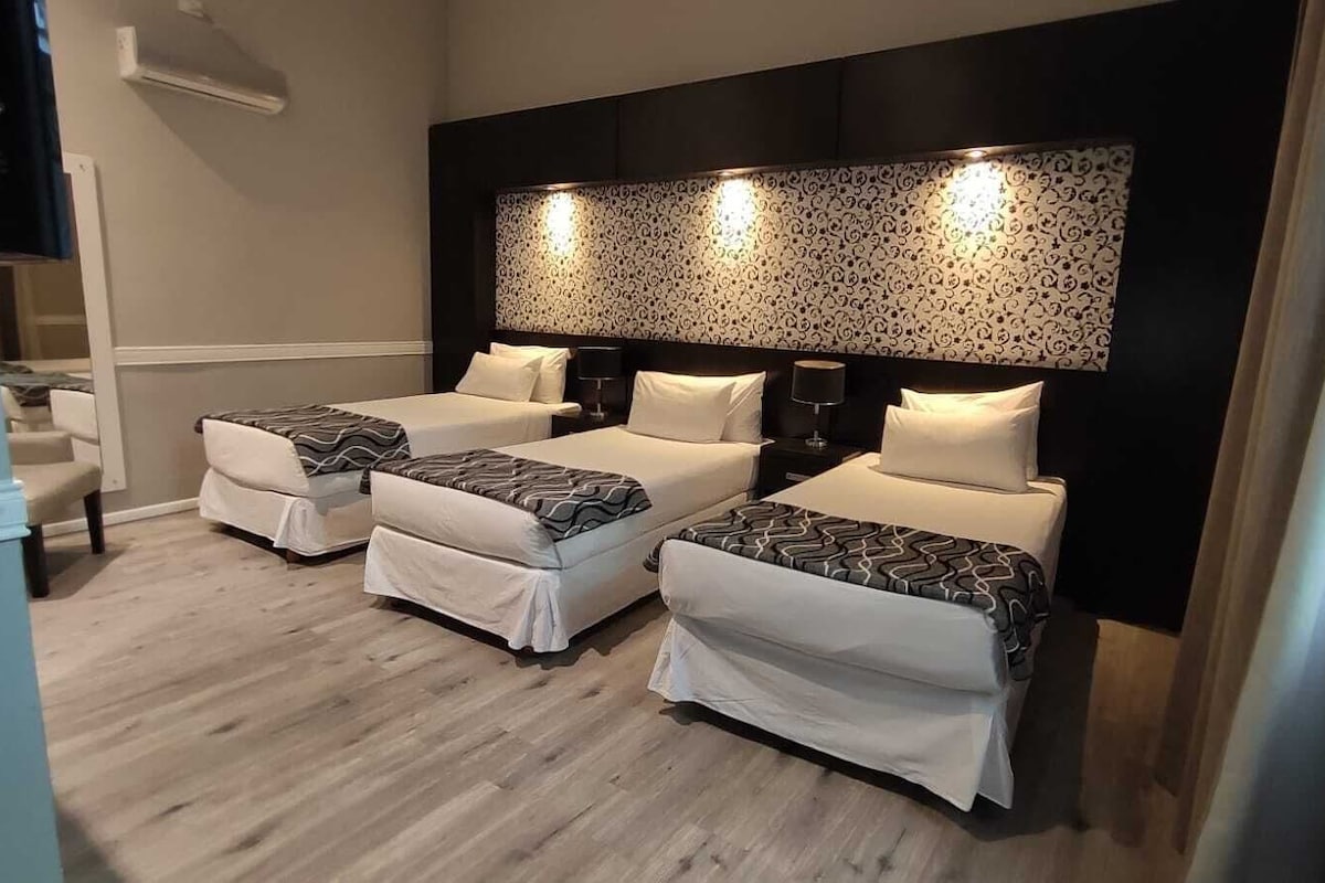 A hotel room with two single beds, a small seating area, and a large wall-mounted light fixture.
