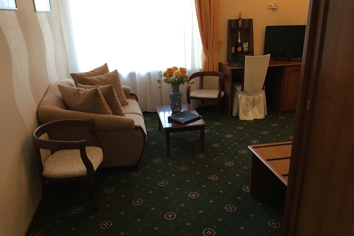 A living room with a sofa, two armchairs, a coffee table, a vase with flowers, a television, and a cabinet.