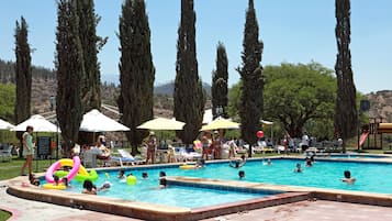 Una piscina al aire libre, sombrillas, sillones reclinables de piscina