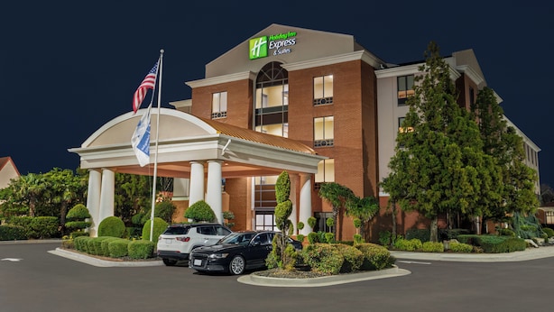 Un bâtiment de l’hôtel Holiday Inn Express, avec une entrée couverte, un drapeau et un parking rempli de voitures.