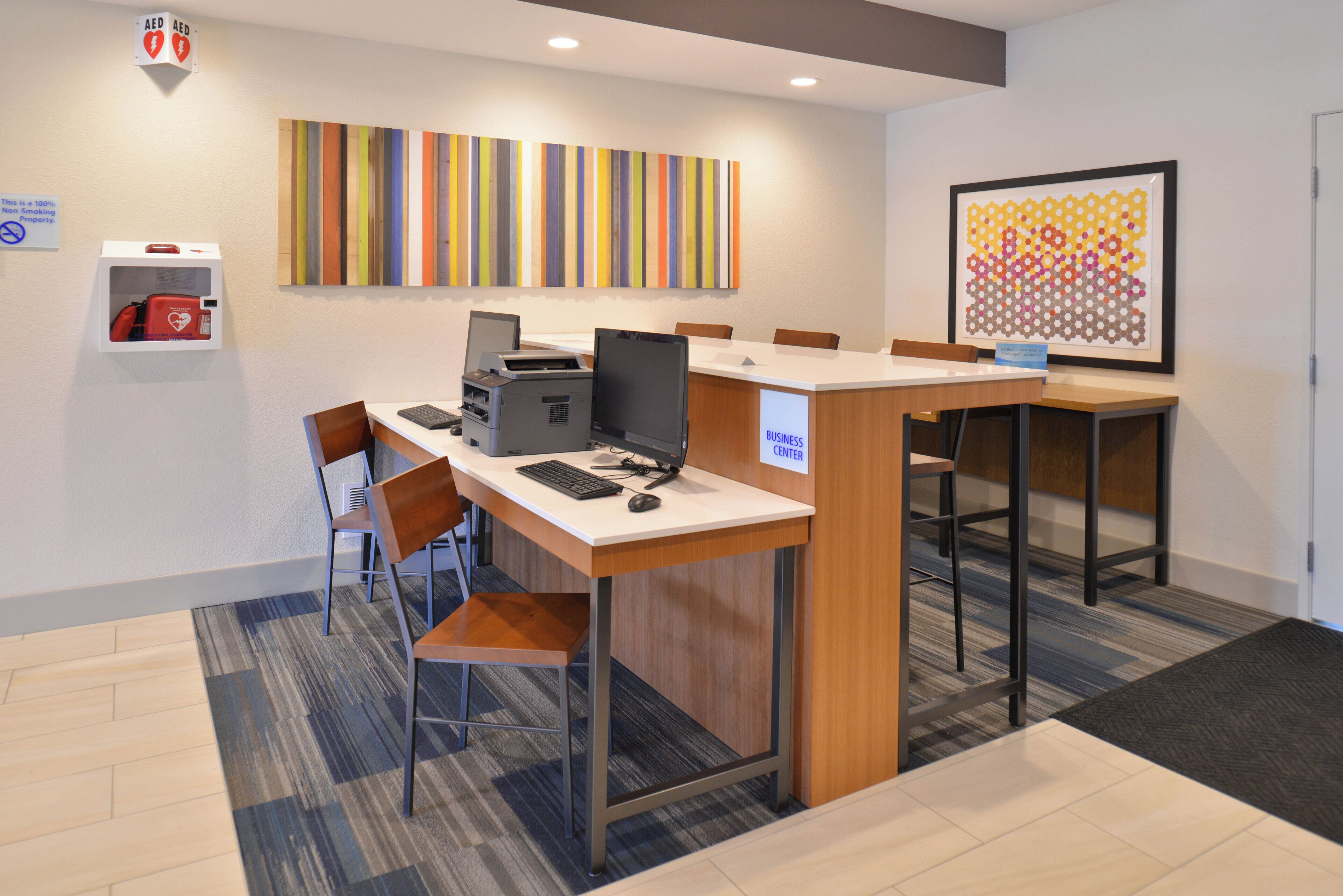 A business center with a reception desk, computers, chairs, and a fire extinguisher.
