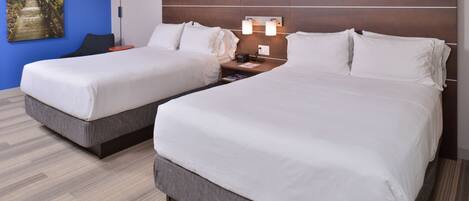 A hotel room with two beds, a nightstand, a lamp, and a painting on the wall.
