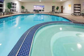 An indoor swimming pool with clear blue water, surrounded by lounge chairs and a tiled deck. - Holiday Inn Express and Suites Stevens Point by IHG (Stevens Point)