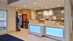 A reception area with a Coca-Cola fridge, a 'smartwater' sign, and a modern reception desk with illuminated panels. - Holiday Inn Express and Suites Stevens Point by IHG (Stevens Point)
