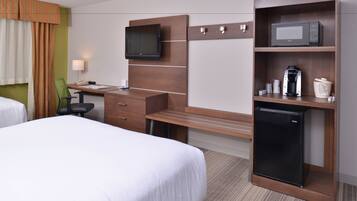 A hotel room with two beds, a desk with a chair, a television, a microwave, a coffee maker, and a mini-fridge.