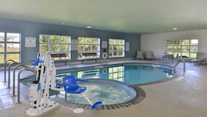 An indoor swimming pool with a pool lift, lounge chairs, and a bench. - Holiday Inn Express and Suites Stevens Point by IHG (Stevens Point)
