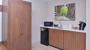 A kitchen with wooden cabinets, a microwave, a sink, and a coffee maker. - Holiday Inn Express and Suites Stevens Point by IHG (Stevens Point)