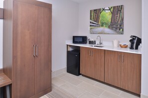 A kitchen with wooden cabinets, a microwave, a sink, and a coffee maker. - Holiday Inn Express and Suites Stevens Point by IHG (Stevens Point)